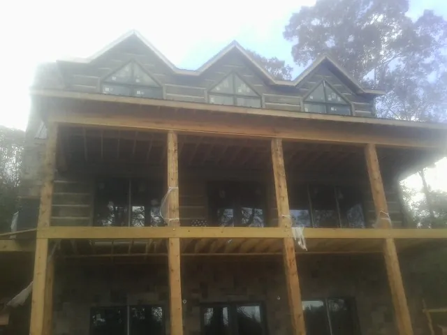 Dormers and porch framing on a large log home under construction — Roof Coating work by our crew in Norman Park