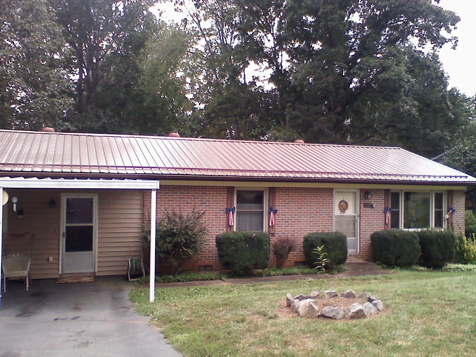 Bronze metal roof and carport on a brick ranch home — Roof Repair work by our crew in Norman Park